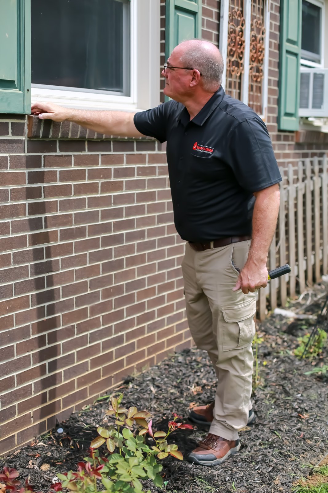 Joseph Caruso inspecting a home exterior in a black ABCHI shirt
